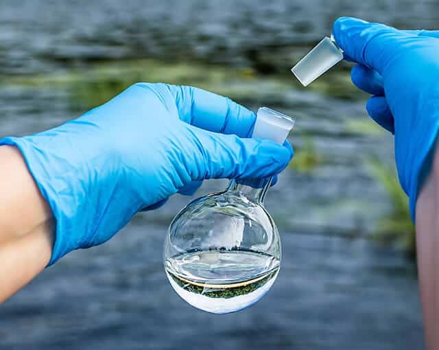 foto di un esperto che mette in un ampolla da laboratorio l'acqua da analizzare