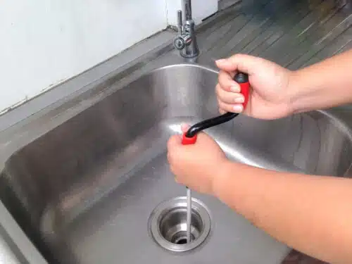 addetto idraulico che disostruisce un lavandino in acciaio